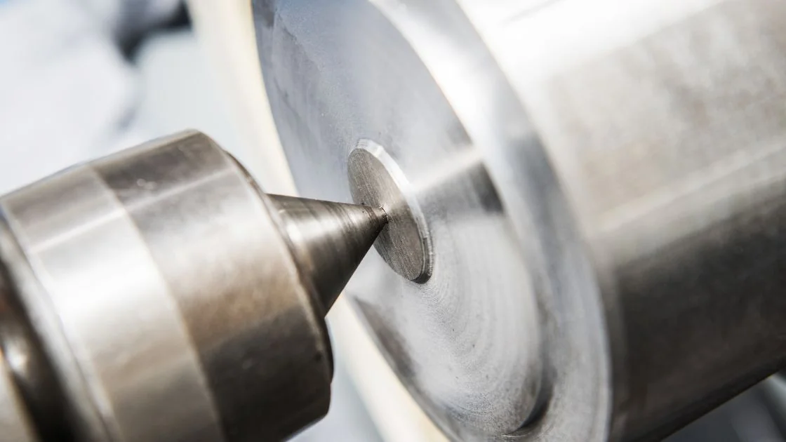 Wiertło metalowe wierci otwór w stalowym cylindrze.
